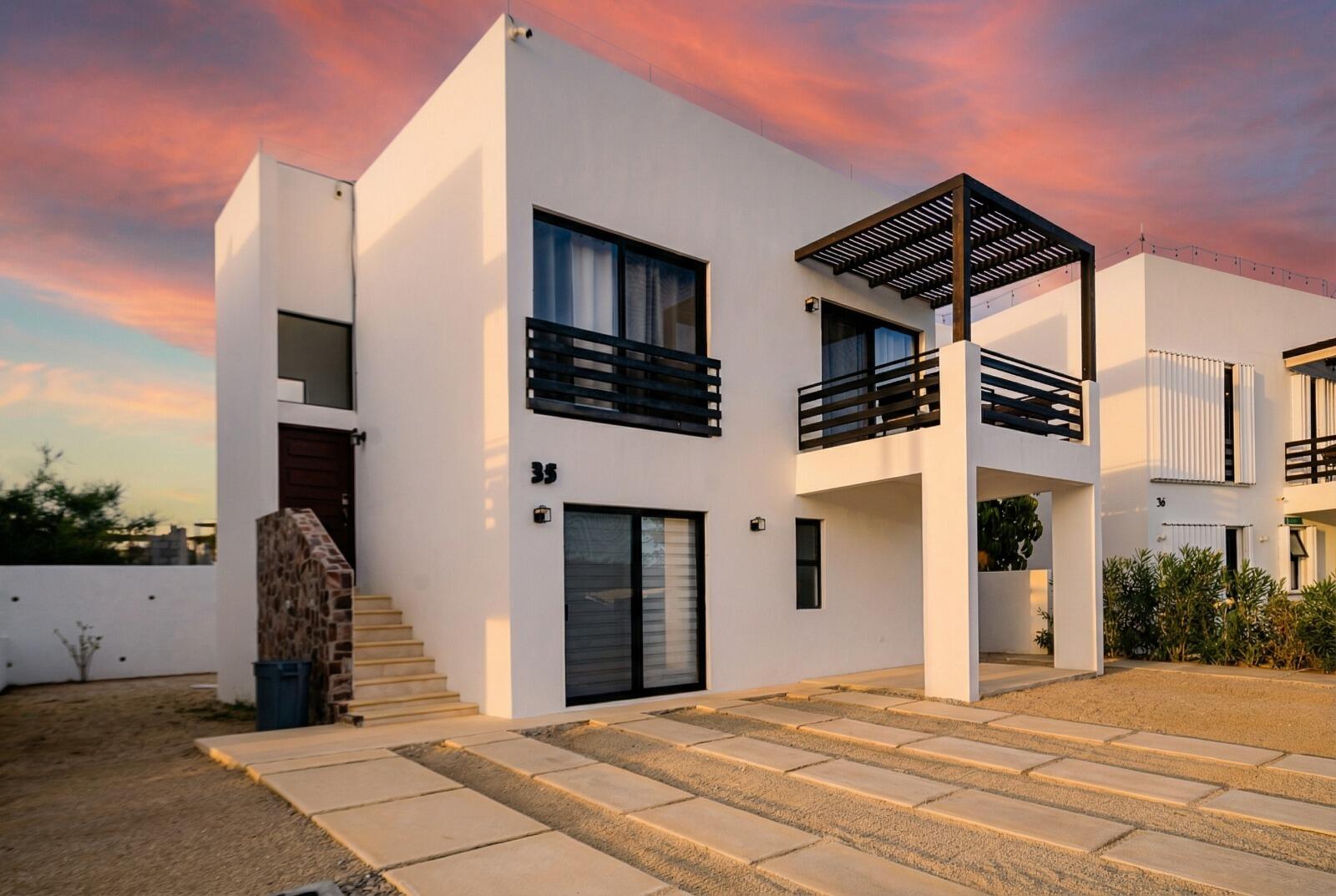 Los Cabos Casa Mex-Agaves Situated within the Casa Mexicana - Agaves community, this thoughtfully designed three-bedroom residence offers a functional and well-planned layout. The main level features a bedroom with an en-suite bathroom and walk-in closet, ideal for guests, multigenerational living, or those seeking stair-free access.A spacious outdoor terrace on the first floor, surrounded by tropical landscaping, provides a serene setting for both relaxation and entertaining. With multiple seating areas, it stands out as a unique feature within Casa Mexicana. The upper level includes two additional bedrooms, each with en-suite bathrooms and walk-in closets, along with the home's main living and kitchen areas. The indoor spaces are seamlessly connected to an additional terrace, enhancing the home's indoor-outdoor living appeal.Additional features include a dedicated laundry area, a two-car garage, and accordion-style hurricane shutters, combining comfort with practicality and peace of mind. for sale